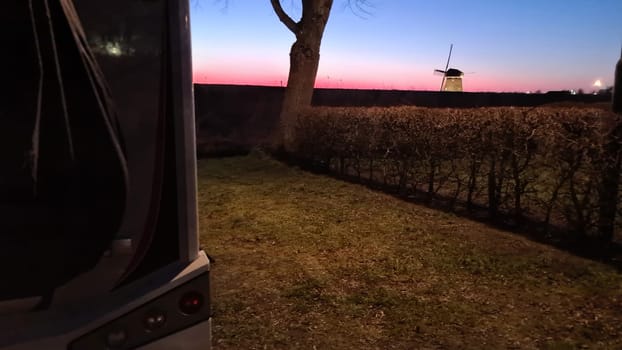Camper van in the sunset in the background a Dutch windmill
