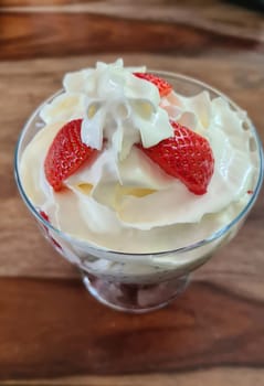 Homemade strawberry ice cream made from fresh berries with basil in glass bowl on gray background. soft focus.