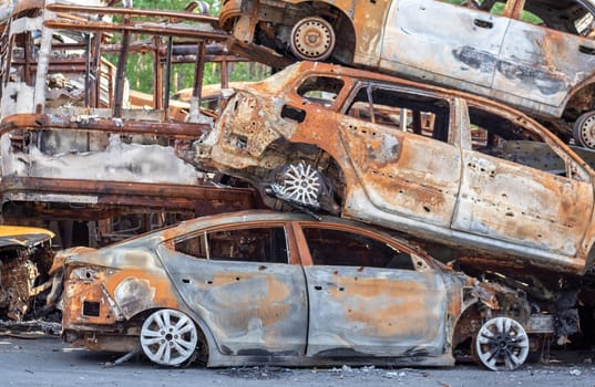A view of burnt-out cars after rocket attacks by the Russian military. War of Russia against Ukraine. Civil vehicle after the fire. Cemetery of cars in the city of Irpin. Rusty pile of metal