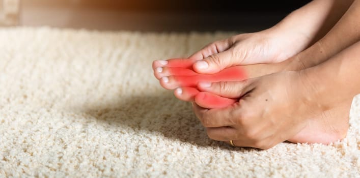 Foot pain, Asian woman holds her toe injury feeling pain her foot at home, female suffering from feet ache use hand massage relax muscle from toe in house interior, Healthcare problems medical concept