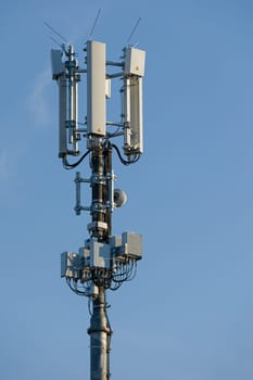 antenna mast with defferent antennas for mobile radio communications in front of blue sky