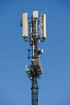 antenna mast with defferent antennas for mobile radio communications in front of blue sky