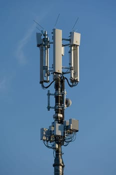 antenna mast with defferent antennas for mobile radio communications in front of blue sky