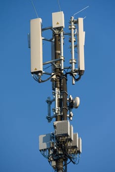 antenna mast with defferent antennas for mobile radio communications in front of blue sky