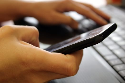 The girl sits at a laptop and holds a smartphone in her hands. Business concept. Online Shopping..