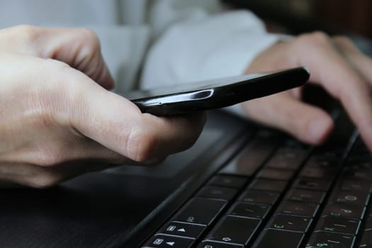 The girl sits at a laptop and holds a smartphone in her hands. Online Shopping. Business concept. .