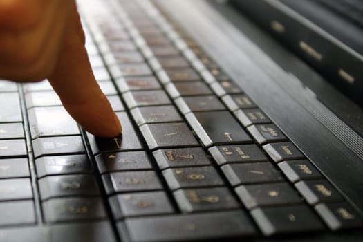 Finger of a female hand press a key on the keyboard of the laptop. Payment Security Concept..