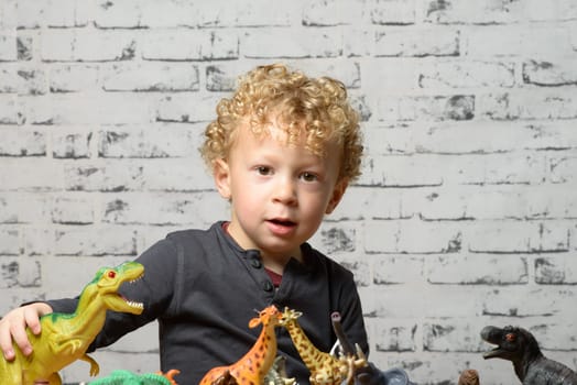 a little child plays with toys animals and dinosaurs
