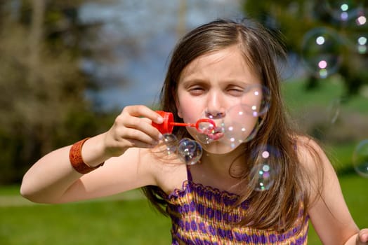 a little girl making soap bubbles in nature