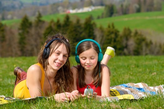 Mom and daughter listening music in nature