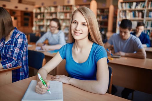 Happy teenage girl sitting by desk at lesson