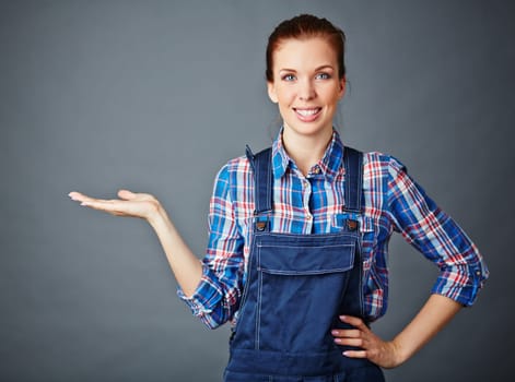 Happy young woman in coveralls keeping her palm open