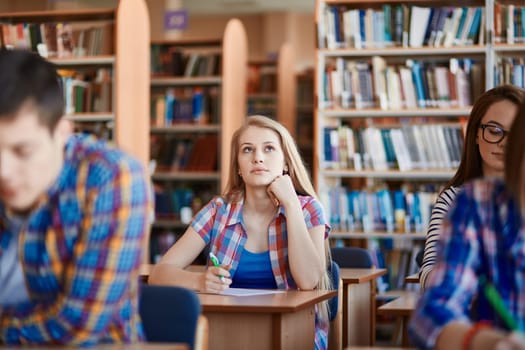 Pensive girl sitting at the desk at lesson in college