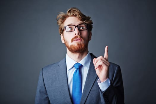 Modern businessman with beard keeping his forefinger pointing up