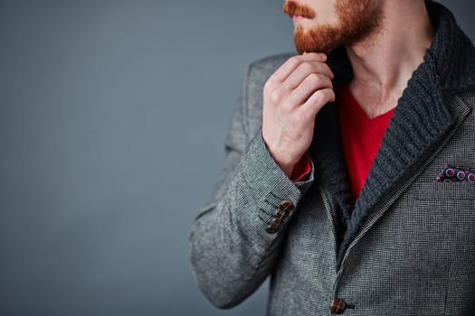 Pensive young man in smart casualwear touching his beard