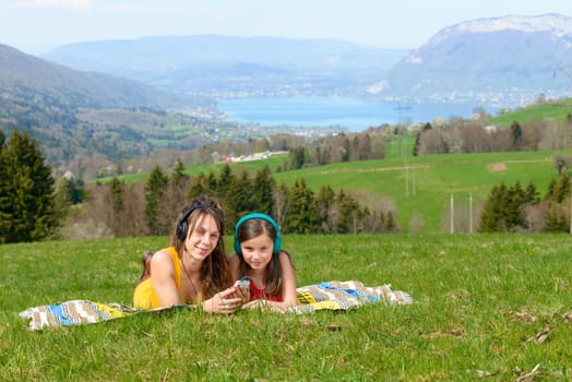 Mom and daughter listening music in nature