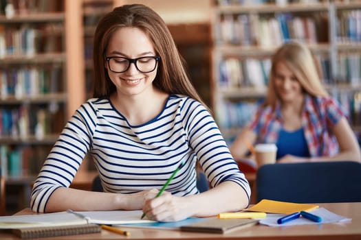 Happy girl in eyeglasses making notes at lesson
