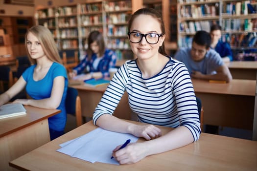 Happy teenage student looking at camera in working environment
