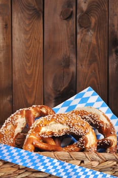 Three original Bavarian lye pretzels with salt in front of a wooden wall