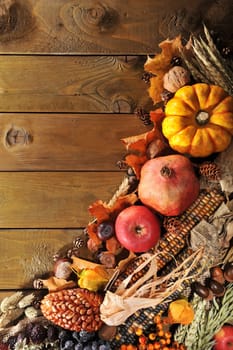 Pumpkins,pomegranate,apple,nuts,berries,corn and cereals on old weathered wooden boards