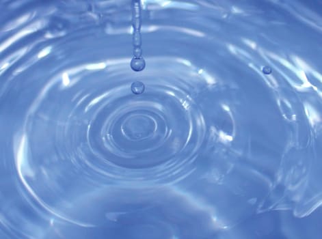 Water drop falling into water making a perfect droplet splash..
