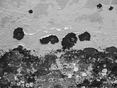 Format-filling view of a metal wall with chipped blue paint in various shades of blue in black and white.