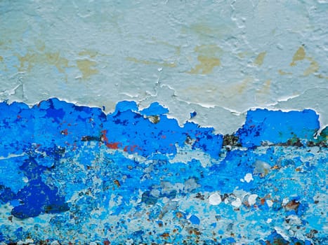 Format-filling view of a metal wall with chipped blue paint in various shades of blue.