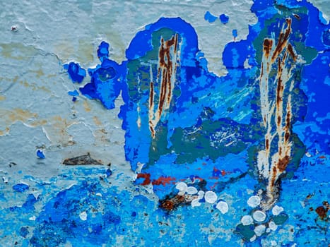 Format-filling view of a metal wall with chipped blue paint in various shades of blue.