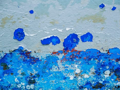 Format-filling view of a metal wall with chipped blue paint in various shades of blue.