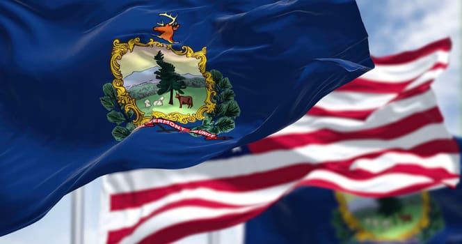 The Vermont state flag waving along with the national flag of the United States of America. Vermont is a state in the New England region of the United States
