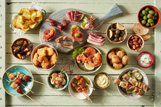 Top view of assorted snacks with kebabs placed near seafood and fried chicken served in bowls on table with assorted sausages