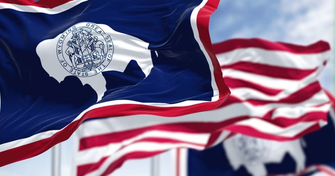 The Wyoming state flag waving along with the national flag of the United States of America. Wyoming is a state in the Mountain West subregion of the Western United States