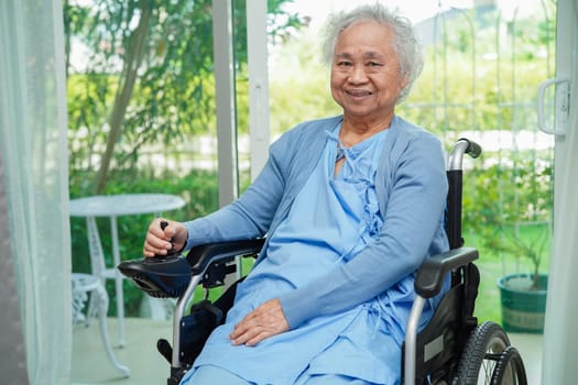 Asian elderly woman disability patient sitting on electric wheelchair in park, medical concept.