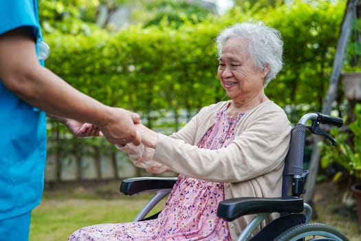 Caregiver help Asian elderly woman disability patient in nursing hospital, medical concept.