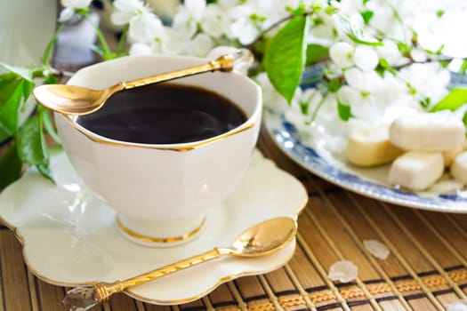 Breakfast with morning coffee cup and white cherry flowers on blossom branch. Concept nostalgia, memories or tenderness.