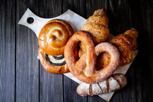 Bread sweet buns on rustic wood, flat lay on dark textured background