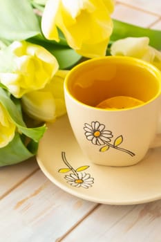 still life tea mug and bouquet of yellow tulips white fabric, vertical image