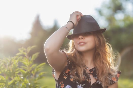 Portrait of posing attractive  young woman in black  straw hat in outside. Horizontally.