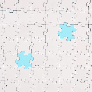 White jigsaw on a blue background, missing parts, working together as a team, searching for solutions, the last piece