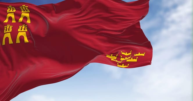 The Region of Murcia flag waving in the wind on a clear day. Region of Murcia is an autonomous community of Spain located in the southeast part of the Iberian Peninsula
