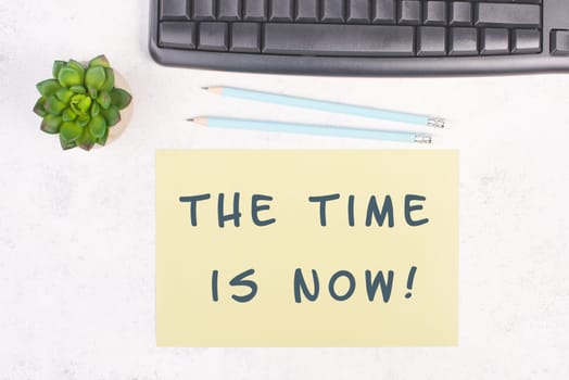 The phrase the time is now is standing on a paper, a pen, computer keyboard and a cactus, brainstorming for new business ideas, startup concept, home office desk