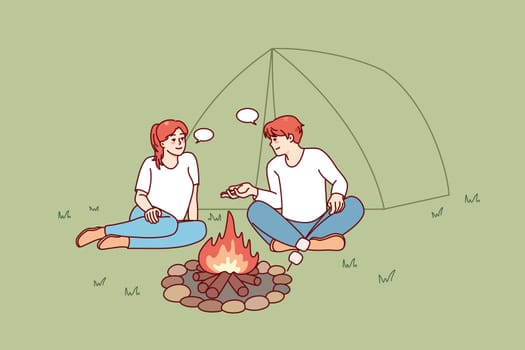 Happy man and woman sitting near campfire in forest. Smiling couple relax at wood camp near fire together. Nature recreation concept. Vector illustration.