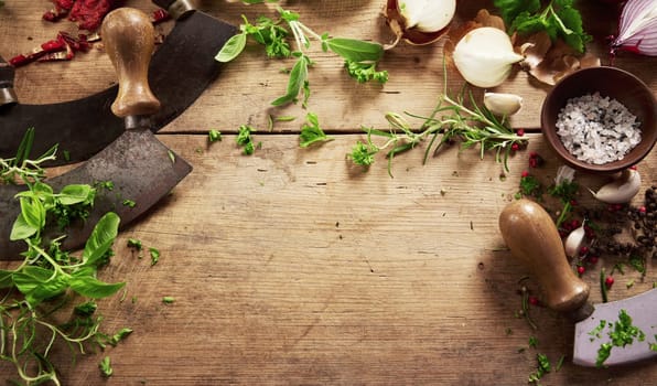 From above of old fashioned mezzaluna knives placed on wooden table with fresh greens during cooking process in light kitchen