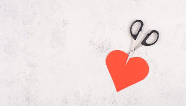 Red heart cut by the scissors, symbol for broken relationship, love and emotion concept, divorce and breakup problems