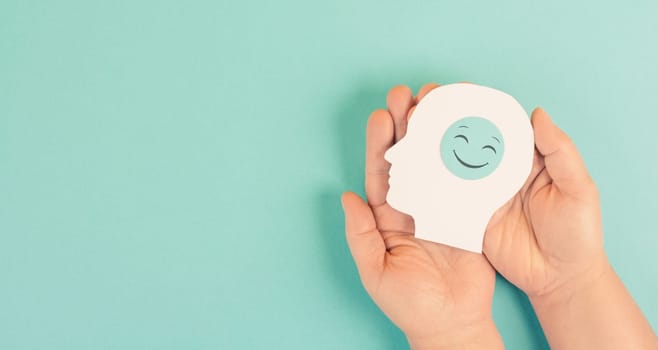 Holding a head with a smiling face in the hands, mental health concept, positive mindset, support and evaluation symbol