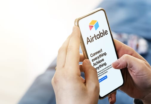 San Francisco, CA, US, May 2022: Female hands holding a phone with Airtable company web page on screen in her living room. Airtable is a cloud collaboration service