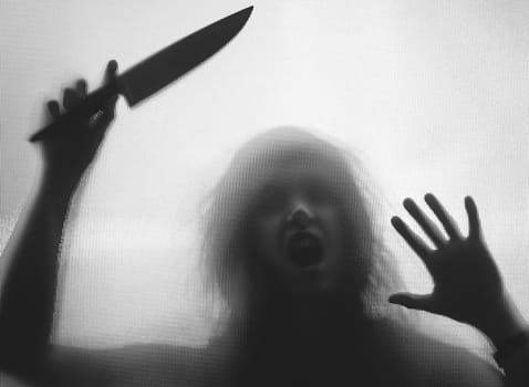 Horror, halloween background - Shadowy figure behind glass holding a knife