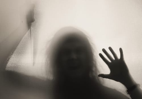 Horror, halloween background - Shadowy figure behind glass holding a knife