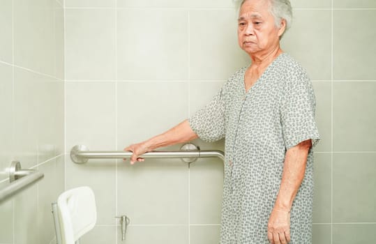 Asian elderly old woman patient use toilet support rail in bathroom, handrail safety grab bar, security in nursing hospital.