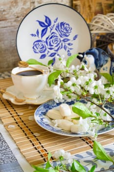 Morning relax, breakfast dishes and decorative elements painted in the style of Gzhel, tea, coffee and white flowers of cherry. Vertical image